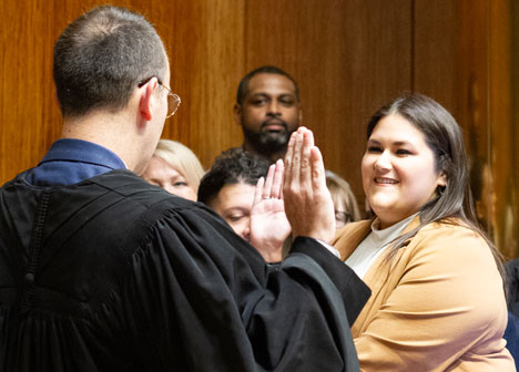 A judge administering the oath of office to a smiling woman.