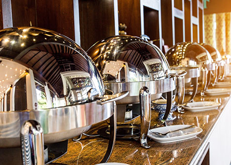 Silver chafing dishes lined up on buffet table