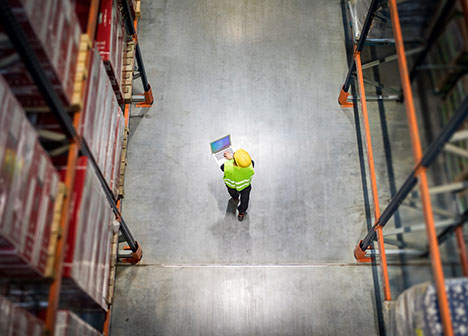 Bird's eye view of warehouse and person walking with computer