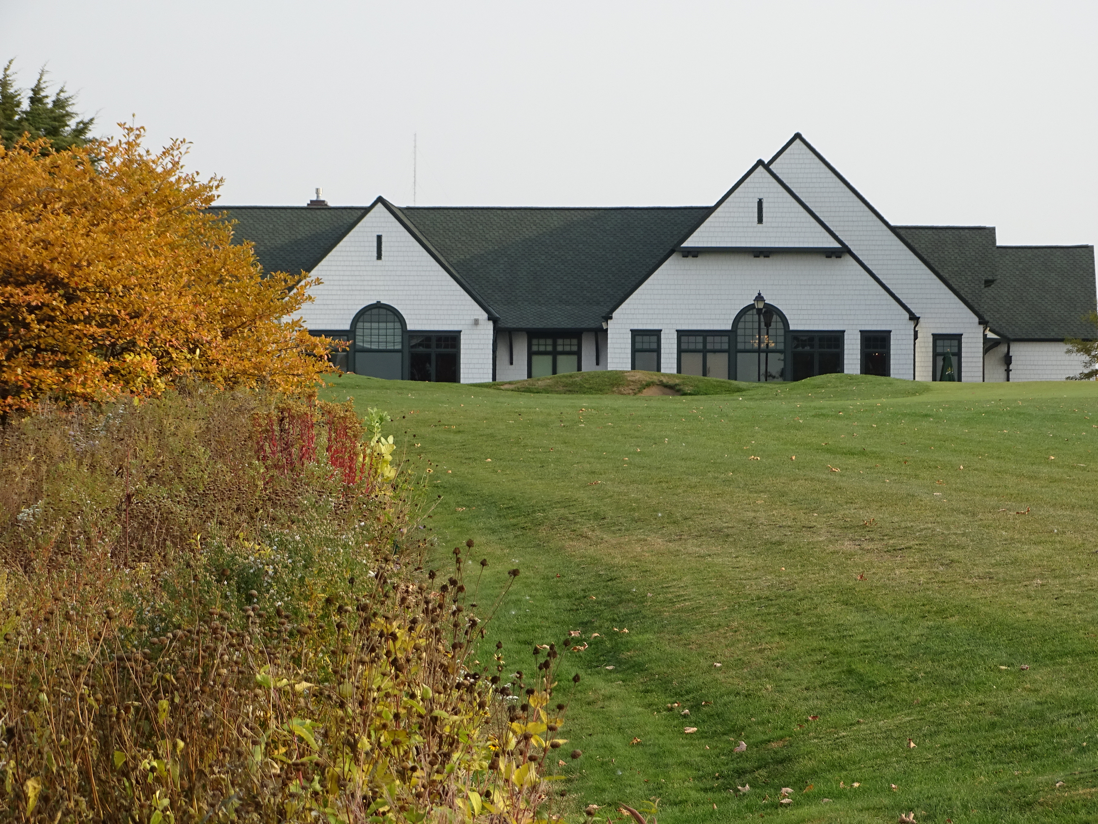 White building in the background of orange and red trees 