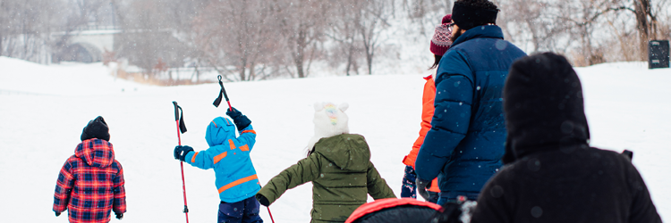 Adults and children in winter attire walking in snow