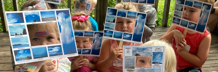 Children holding blue square frames where they are peaking their eyes out from.