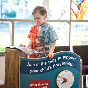 Boy reading in children's area of Ramsey County Library - White Bear Lake